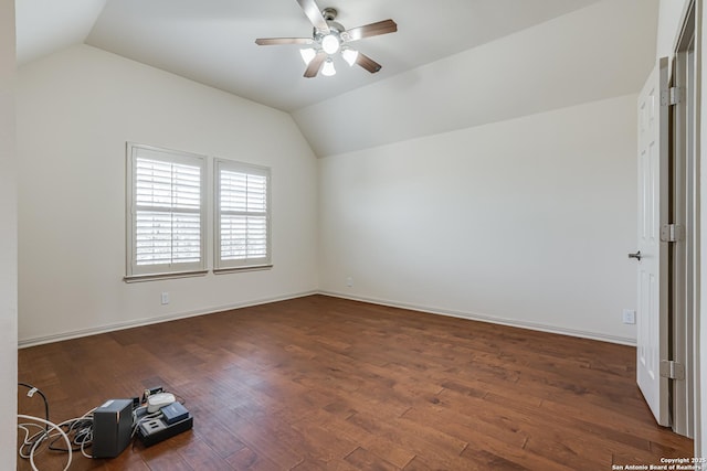 unfurnished room with baseboards, dark wood-style floors, a ceiling fan, and vaulted ceiling