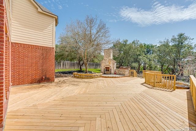 wooden deck with fence and an outdoor stone fireplace