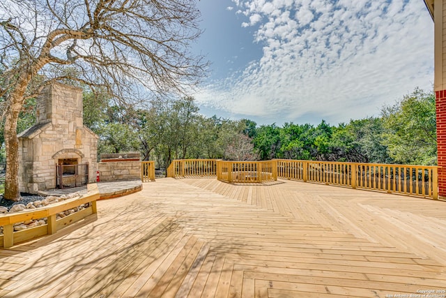 wooden terrace featuring an outdoor stone fireplace