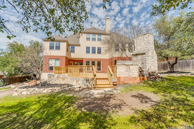 back of property featuring brick siding, a wooden deck, a chimney, and fence