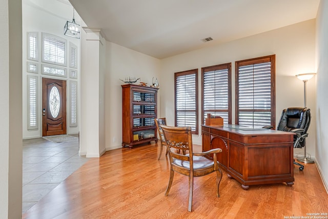 office space featuring baseboards, visible vents, and light wood finished floors