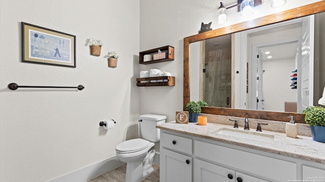 bathroom featuring baseboards, toilet, a stall shower, and vanity