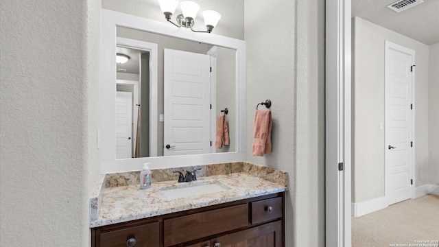 bathroom with visible vents, vanity, and a textured wall