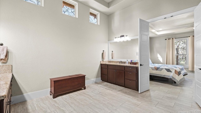 ensuite bathroom with plenty of natural light, connected bathroom, vanity, and baseboards