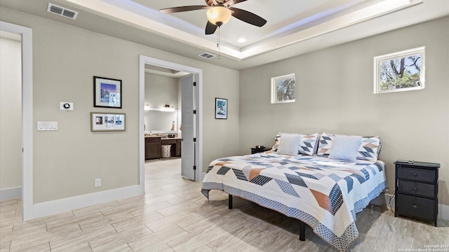 bedroom with visible vents, wood finish floors, baseboards, and a tray ceiling