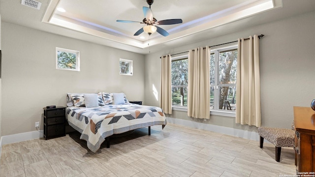 bedroom featuring a raised ceiling, multiple windows, and visible vents