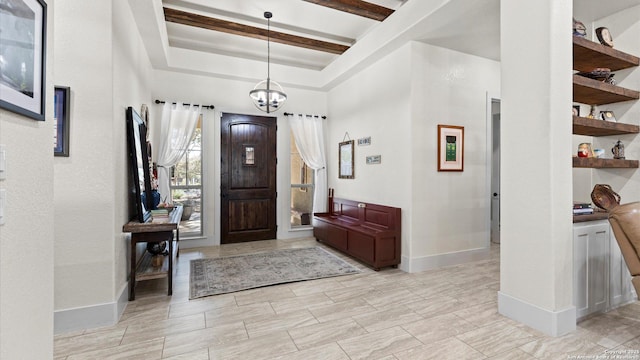 entryway featuring beam ceiling, a notable chandelier, a raised ceiling, and baseboards