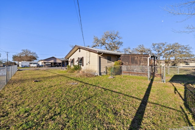 rear view of property featuring a gate, a yard, and fence