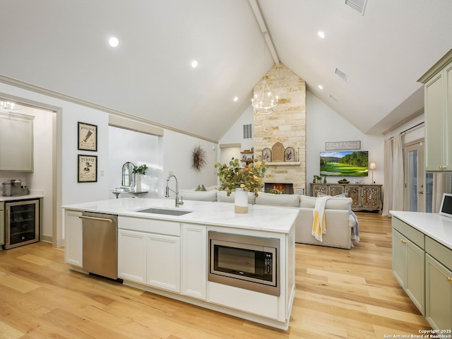 kitchen with visible vents, a sink, a stone fireplace, appliances with stainless steel finishes, and open floor plan