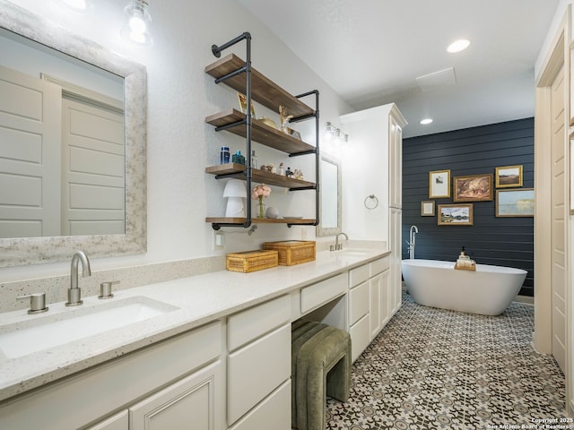 full bathroom featuring a sink, a freestanding tub, recessed lighting, and double vanity