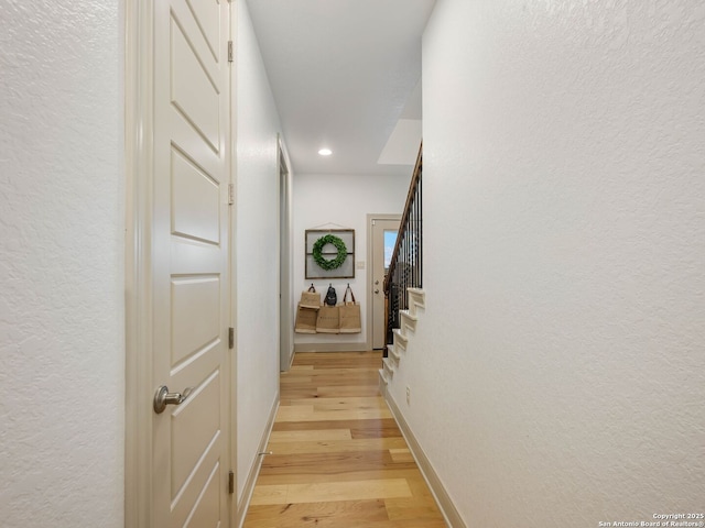 hall with stairs, recessed lighting, light wood-style floors, and baseboards