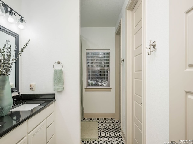 full bath featuring vanity and baseboards