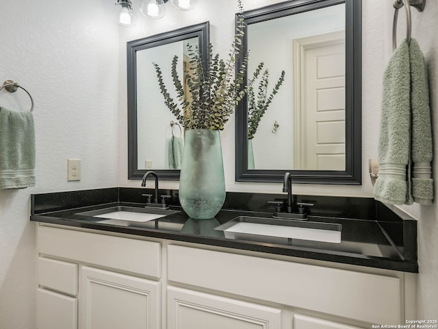 full bath with a sink, double vanity, and a textured wall