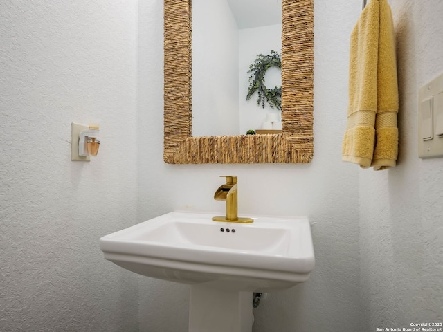 bathroom featuring a textured wall and a sink