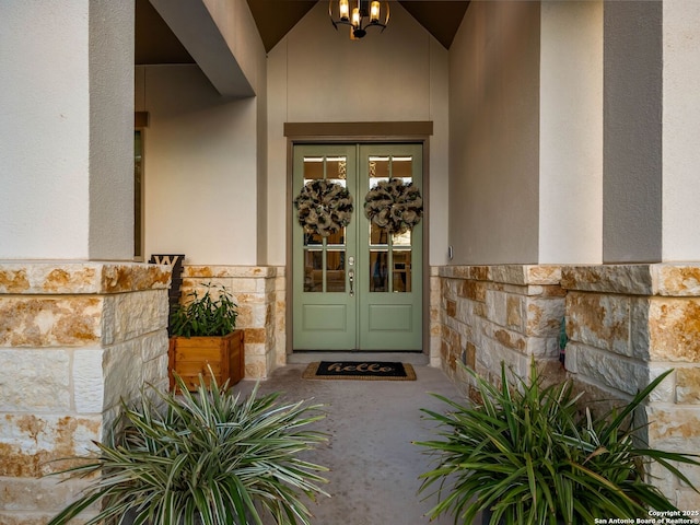 property entrance featuring french doors, stone siding, and stucco siding