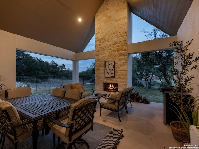 view of patio / terrace with outdoor dining area, fence, and an outdoor stone fireplace