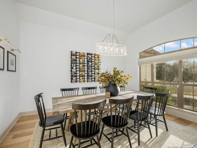 dining room with a notable chandelier, light wood-style floors, baseboards, and a wealth of natural light