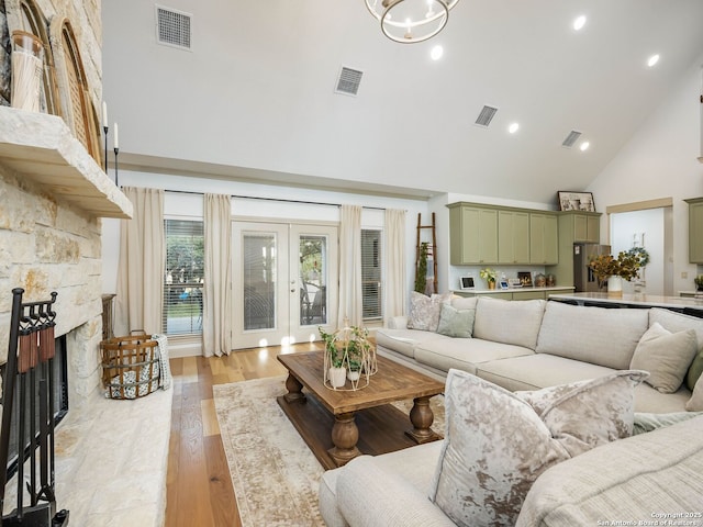 living area with visible vents, high vaulted ceiling, and a fireplace