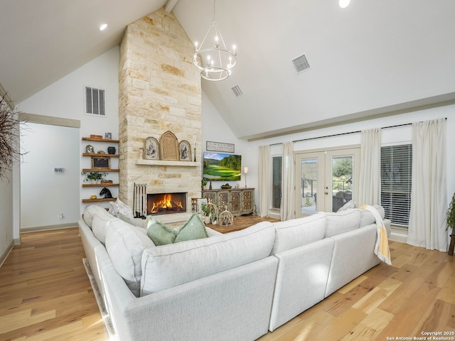 living area with visible vents, french doors, a stone fireplace, and light wood-type flooring