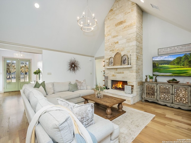 living room with visible vents, wood finished floors, french doors, an inviting chandelier, and a fireplace