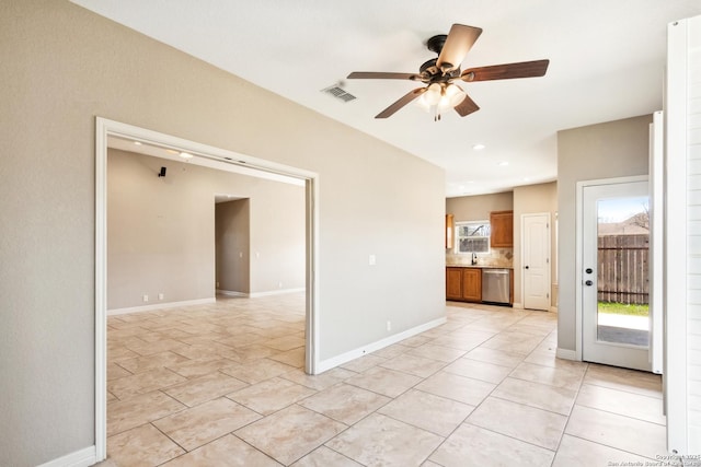 empty room with light tile patterned floors, visible vents, a ceiling fan, and baseboards