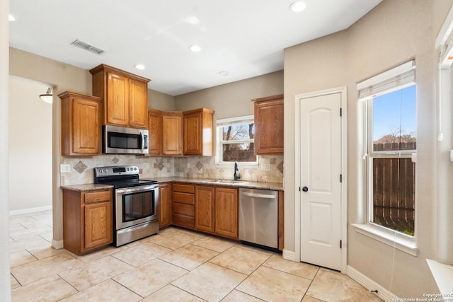 kitchen with brown cabinetry, visible vents, appliances with stainless steel finishes, and decorative backsplash