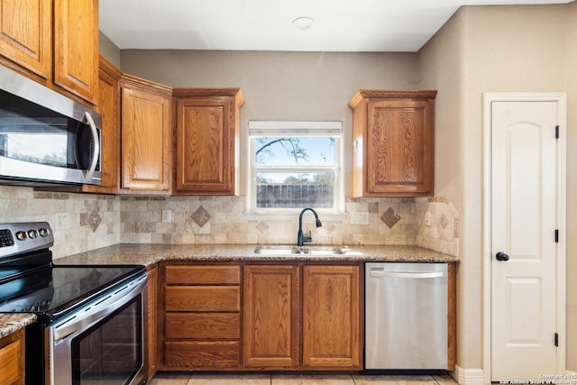 kitchen with brown cabinetry, stainless steel appliances, and a sink