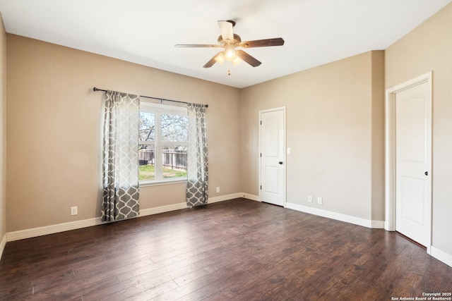 spare room with dark wood-style floors, a ceiling fan, and baseboards