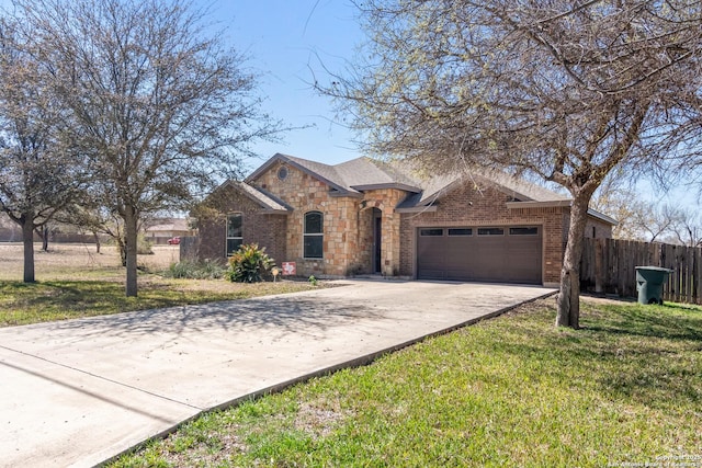 view of front facade with a front yard, fence, concrete driveway, a garage, and brick siding