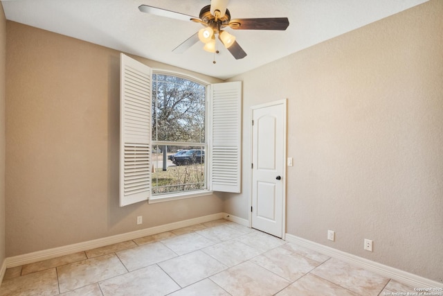 empty room featuring tile patterned floors, baseboards, and a ceiling fan