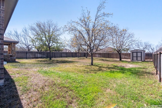 view of yard with an outbuilding, a fenced backyard, and a shed