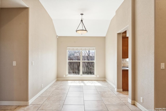 unfurnished room featuring light tile patterned floors, baseboards, and lofted ceiling