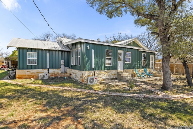 view of front of house with ac unit, entry steps, fence, board and batten siding, and metal roof