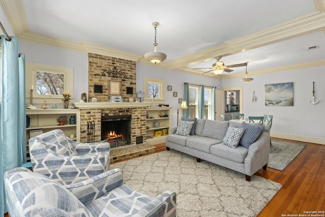 living area featuring visible vents, a fireplace, crown molding, and wood-type flooring