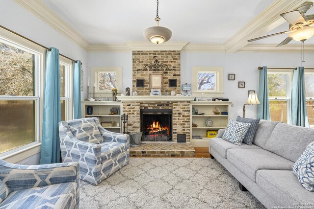 living area featuring a ceiling fan, a brick fireplace, and crown molding