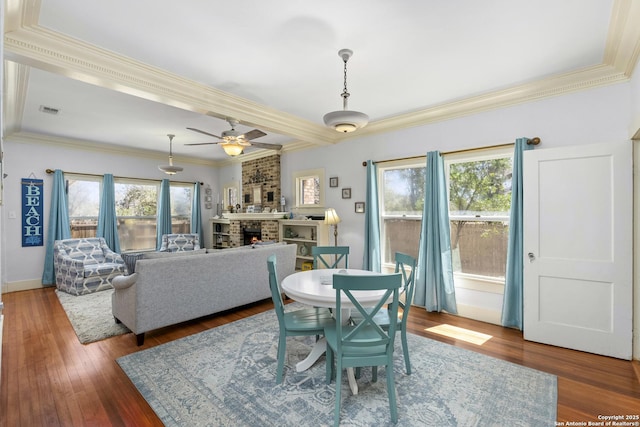 dining space with a brick fireplace, crown molding, a ceiling fan, and hardwood / wood-style flooring