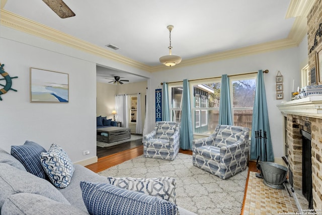 living room featuring visible vents, a fireplace, crown molding, and wood finished floors