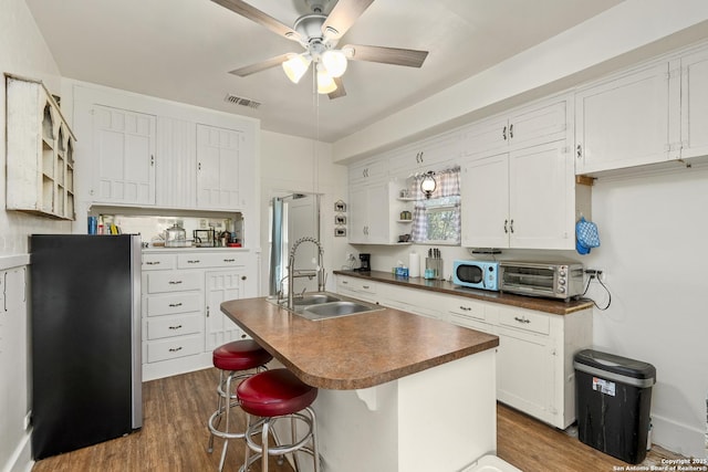 kitchen featuring a sink, open shelves, dark countertops, white cabinetry, and dark wood-style flooring