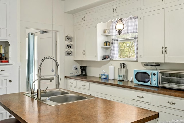 kitchen with a sink, dark countertops, white cabinets, and a toaster