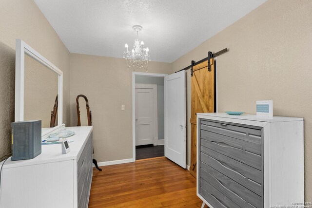 clothes washing area featuring a barn door, baseboards, a notable chandelier, and light wood-style flooring