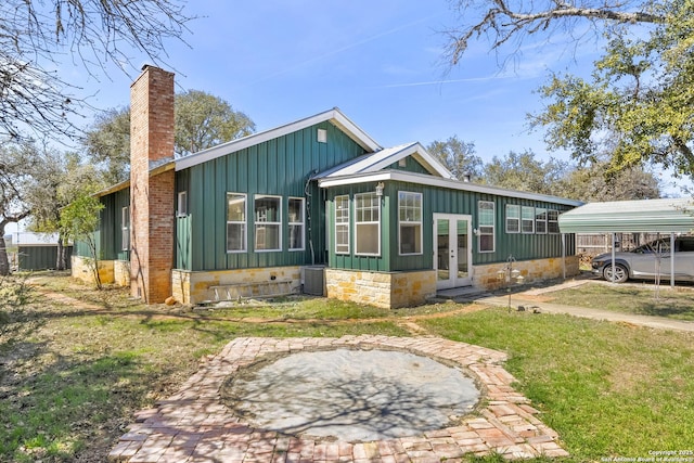 view of front of property with board and batten siding, a front yard, french doors, a chimney, and a carport