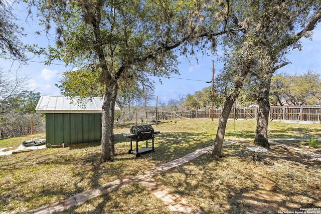 view of yard featuring an outbuilding, a storage unit, and fence