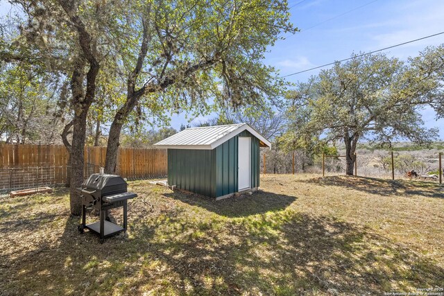 view of yard featuring an outbuilding, a fenced backyard, and a shed