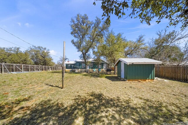 view of yard with an outbuilding, a storage unit, and a fenced backyard