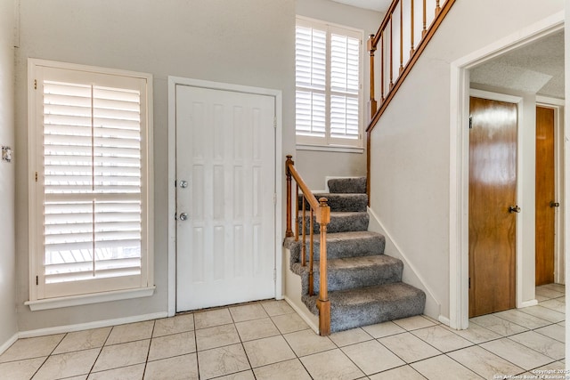 foyer featuring light tile patterned flooring and stairway