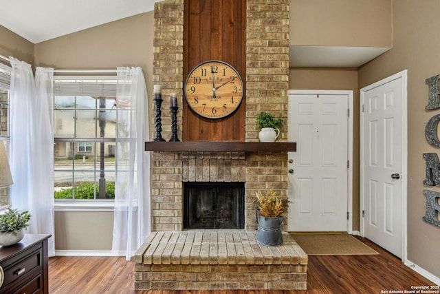 living room featuring lofted ceiling, a brick fireplace, wood finished floors, and baseboards