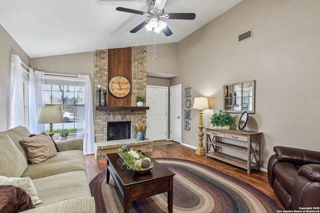 living room with a ceiling fan, wood finished floors, visible vents, baseboards, and a brick fireplace