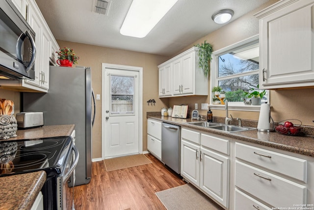 kitchen featuring light wood-type flooring, visible vents, a sink, white cabinetry, and stainless steel appliances