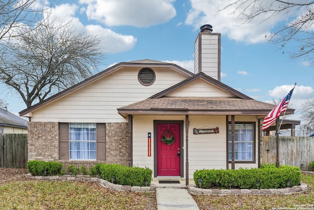 bungalow-style home with brick siding, a shingled roof, a chimney, and fence