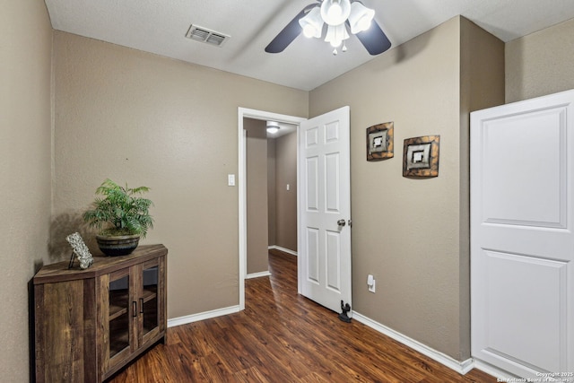 hallway with visible vents, baseboards, and dark wood-style floors